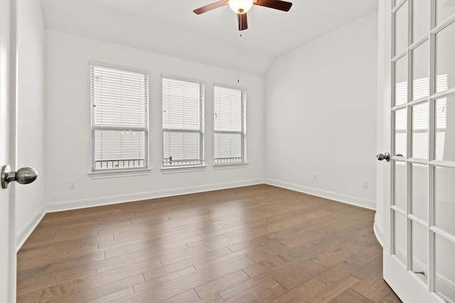 empty room with ceiling fan, baseboards, lofted ceiling, and wood finished floors