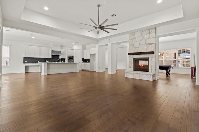 unfurnished living room with a raised ceiling, a ceiling fan, healthy amount of natural light, and recessed lighting