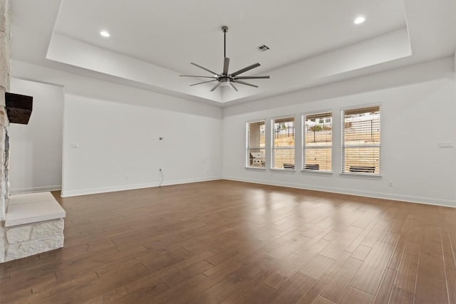 unfurnished living room featuring a tray ceiling, ceiling fan, dark wood-type flooring, baseboards, and recessed lighting
