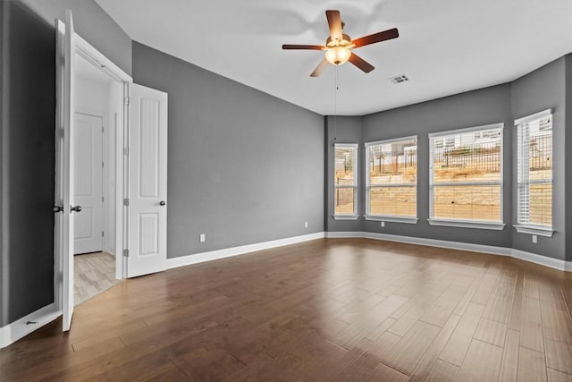 unfurnished room with ceiling fan, dark wood-style floors, and baseboards