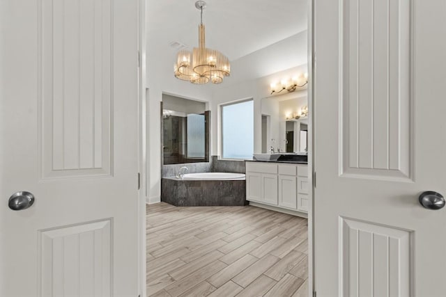 bathroom with a chandelier, a bath, vanity, wood finished floors, and a shower