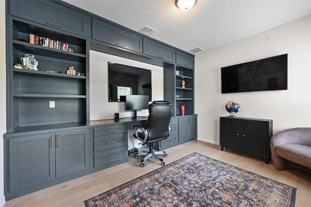 8716 Mina Dr, Austin, TX 78747 - office area with light wood-style flooring, built in study area, built in shelves, and baseboards