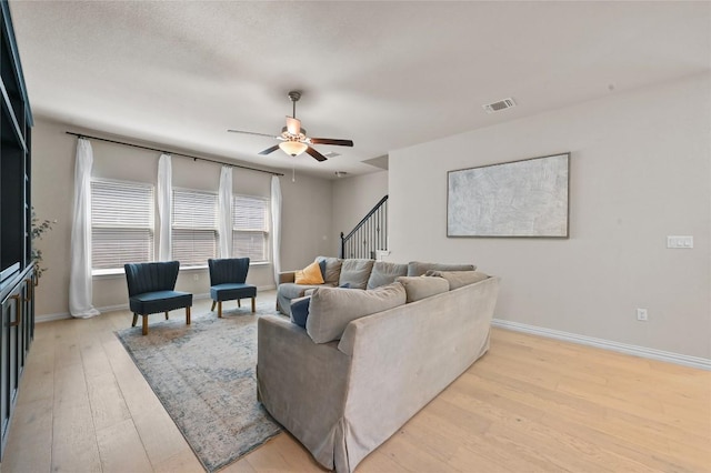 8716 Mina Dr, Austin, TX 78747 - living room with light wood-style flooring, a ceiling fan, baseboards, and stairs