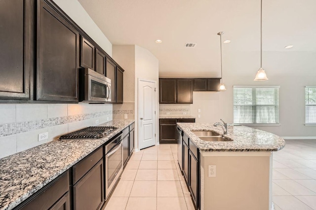 kitchen with stainless steel appliances, a sink, light tile patterned floors, light stone countertops, and recessed lighting
