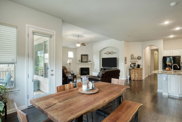 2909 Saint Paul Rivera, Round Rock, TX 78665 - dining room featuring arched walkways, ceiling fan, dark wood-style flooring, a glass covered fireplace, and recessed lighting