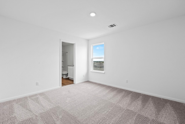 unfurnished bedroom featuring carpet floors, baseboards, and ensuite bath