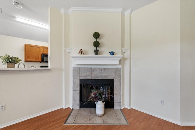 140 Shenandoah Trl, Elgin, TX 78621 - detailed view of wood finished floors, black microwave, baseboards, a tile fireplace, and ornamental molding
