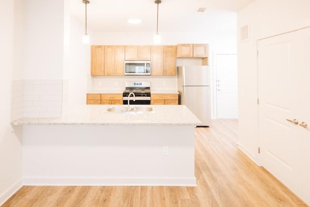 7051 Meadow Lake Blvd Unit 8203, Austin, TX 78744 - kitchen featuring stainless steel microwave, freestanding refrigerator, a peninsula, a sink, and light brown cabinets
