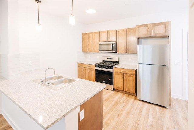 7051 Meadow Lake Blvd Unit 8203, Austin, TX 78744 - kitchen featuring appliances with stainless steel finishes, a sink, a peninsula, decorative backsplash, and light wood-style floors