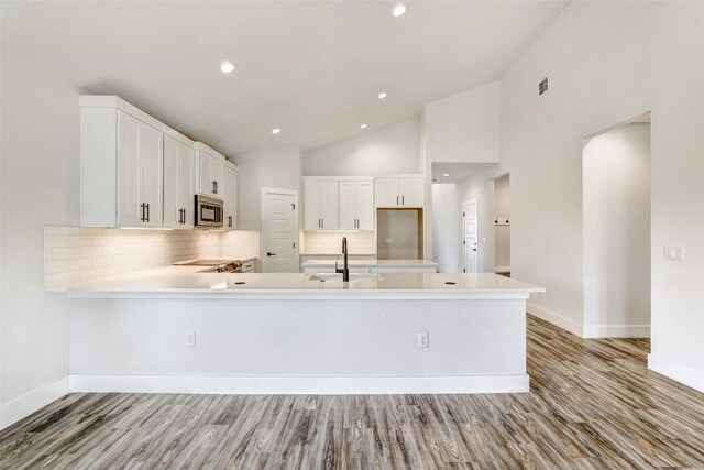 9601 Eloquence Dr, Manor, TX 78653 - kitchen with stainless steel microwave, tasteful backsplash, light countertops, a peninsula, and recessed lighting