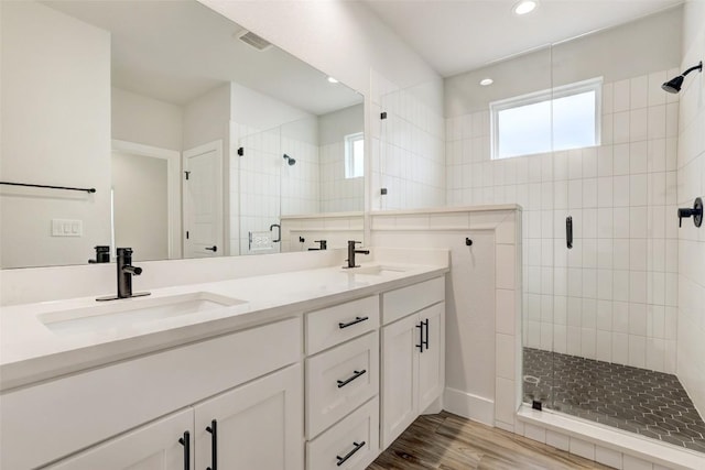 9601 Eloquence Dr, Manor, TX 78653 - bathroom featuring a shower stall, double vanity, wood finished floors, and recessed lighting