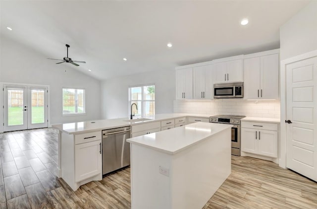 9601 Eloquence Dr, Manor, TX 78653 - kitchen featuring appliances with stainless steel finishes, a peninsula, light wood-style floors, backsplash, and lofted ceiling