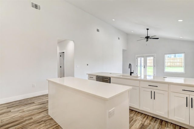9601 Eloquence Dr, Manor, TX 78653 - kitchen featuring a center island, dishwasher, ceiling fan, light wood finished floors, and white cabinetry