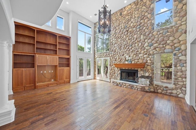 106 Sendera Bonita, Austin, TX 78734 - unfurnished living room with a high ceiling, a chandelier, wood-type flooring, a fireplace, and recessed lighting