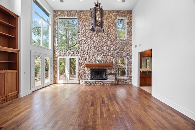 106 Sendera Bonita, Austin, TX 78734 - unfurnished living room featuring a high ceiling, healthy amount of natural light, wood-type flooring, and a stone fireplace