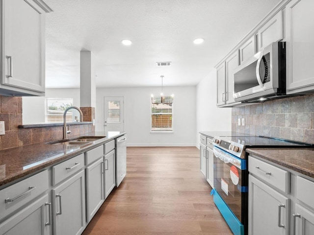 109 Orange Tree Ln, Georgetown, TX 78626 - kitchen with appliances with stainless steel finishes, a sink, light wood finished floors, backsplash, and baseboards