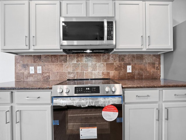 109 Orange Tree Ln, Georgetown, TX 78626 - kitchen with appliances with stainless steel finishes, white cabinetry, tasteful backsplash, and dark stone countertops