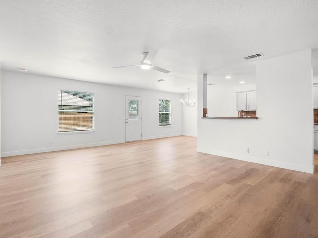 109 Orange Tree Ln, Georgetown, TX 78626 - unfurnished living room with a chandelier, light wood finished floors, a ceiling fan, and baseboards