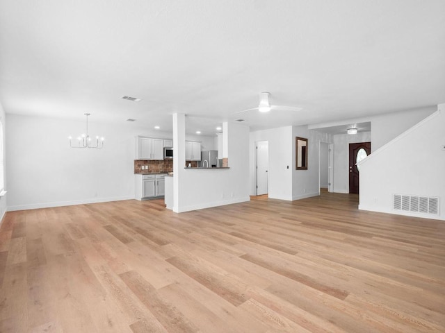 109 Orange Tree Ln, Georgetown, TX 78626 - unfurnished living room with baseboards, a chandelier, light wood-style flooring, and a ceiling fan