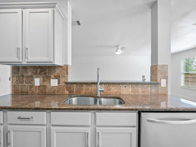 109 Orange Tree Ln, Georgetown, TX 78626 - kitchen featuring stainless steel dishwasher, a sink, decorative backsplash, dark stone counters, and white cabinetry