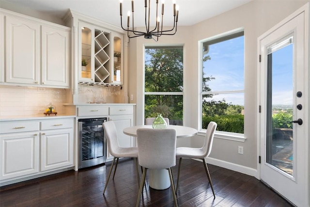 dining room with beverage cooler, a chandelier, a dry bar, dark wood finished floors, and baseboards