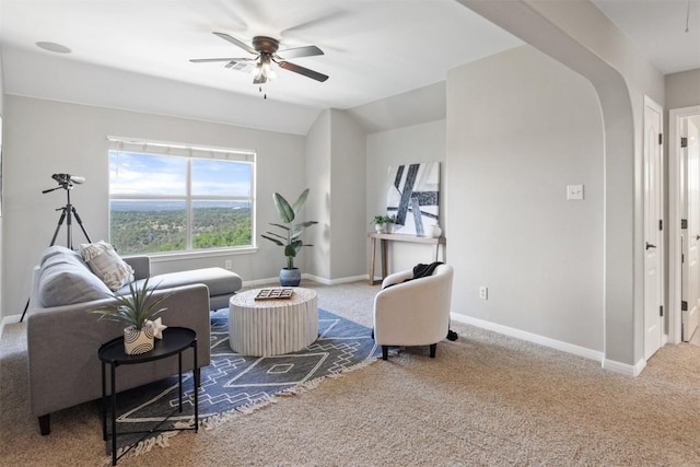 carpeted living room featuring a ceiling fan, baseboards, arched walkways, and lofted ceiling