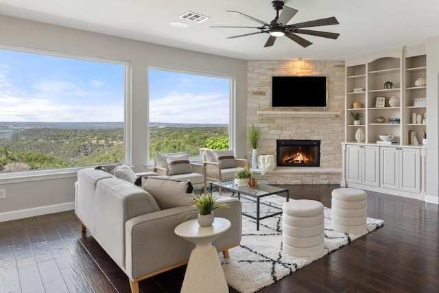 living area featuring baseboards, a ceiling fan, plenty of natural light, and dark wood-style flooring