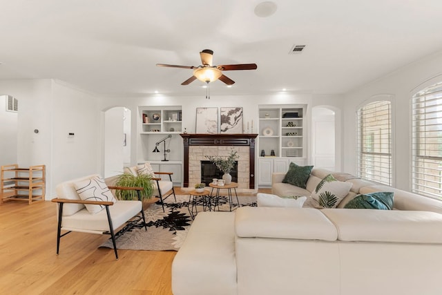 9604 Big View Dr, Austin, TX 78730 - living area with arched walkways, built in shelves, light wood-style flooring, a ceiling fan, and crown molding