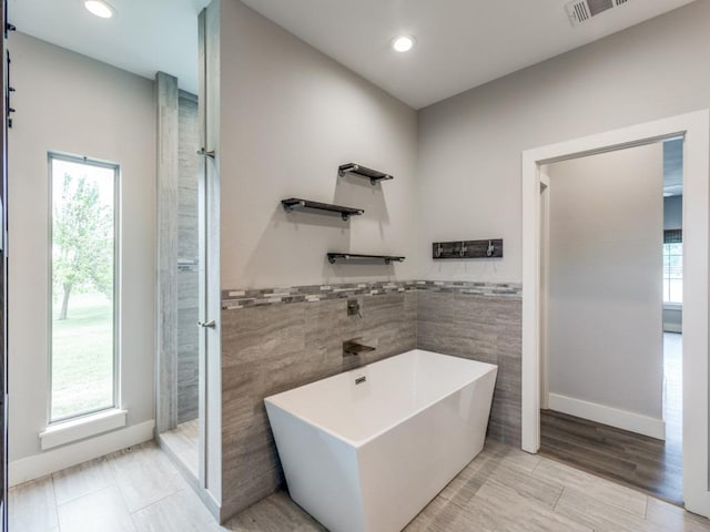 16721 Decker Creek Dr, Manor, TX 78653 - full bath featuring tile walls, a freestanding bath, recessed lighting, and wainscoting