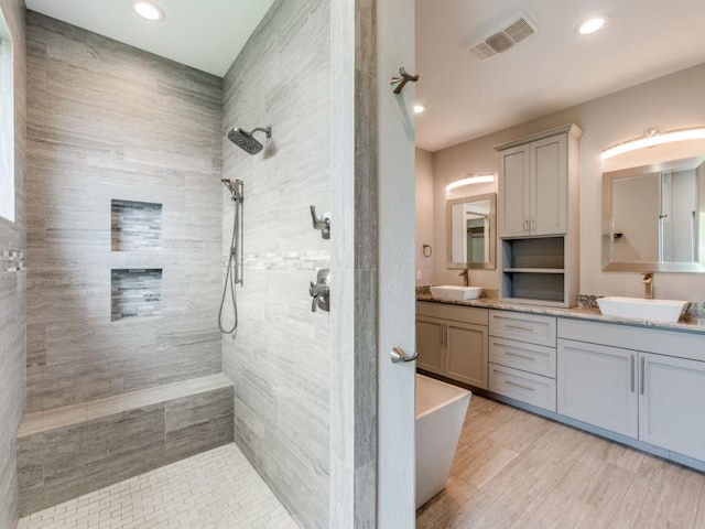 16721 Decker Creek Dr, Manor, TX 78653 - bathroom featuring double vanity, a walk in shower, a soaking tub, recessed lighting, and wood finished floors
