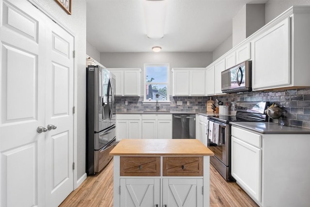 146 Long Shadow Dr, Bastrop, TX 78602 - kitchen with appliances with stainless steel finishes, light wood-style floors, tasteful backsplash, and white cabinetry
