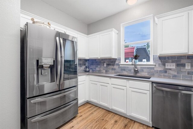 146 Long Shadow Dr, Bastrop, TX 78602 - kitchen with stainless steel appliances, a sink, white cabinets, decorative backsplash, and light wood finished floors