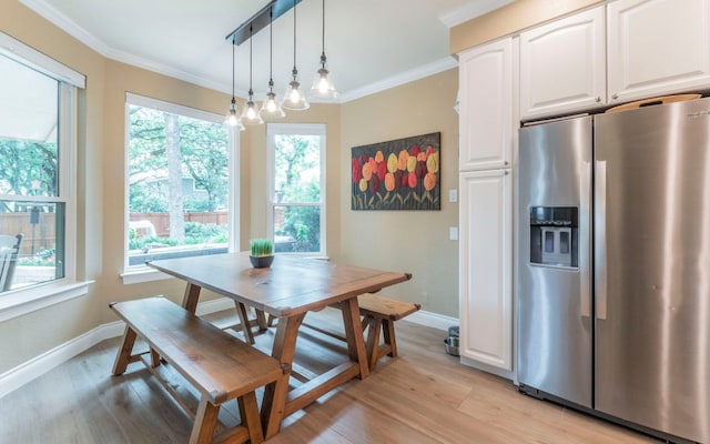 dining room with baseboards, light wood finished floors, and ornamental molding