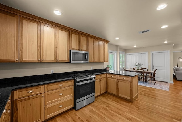 3214 Funston St, Austin, TX 78703 - kitchen featuring stainless steel appliances, a peninsula, light wood-type flooring, recessed lighting, and dark stone countertops