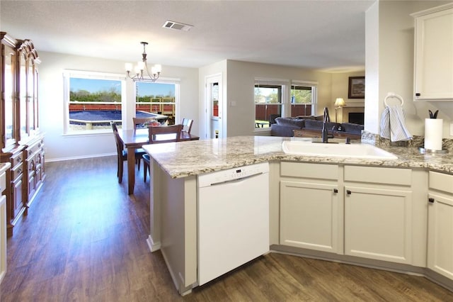 kitchen featuring white dishwasher, a sink, dark wood-style flooring, a chandelier, and a peninsula