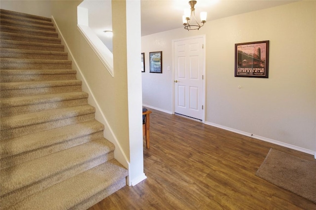 stairway featuring wood finished floors, a chandelier, and baseboards