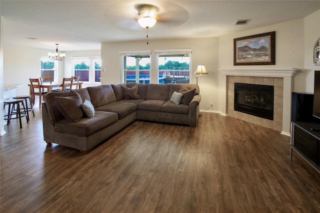 2418 Madeline Loop, Cedar Park, TX 78613 - living area with dark wood-style floors, a chandelier, a tile fireplace, a ceiling fan, and baseboards