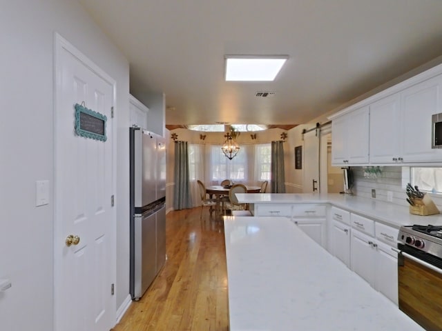 1127 Penion Dr, Austin, TX 78748 - kitchen with appliances with stainless steel finishes, white cabinets, light countertops, and light wood-type flooring