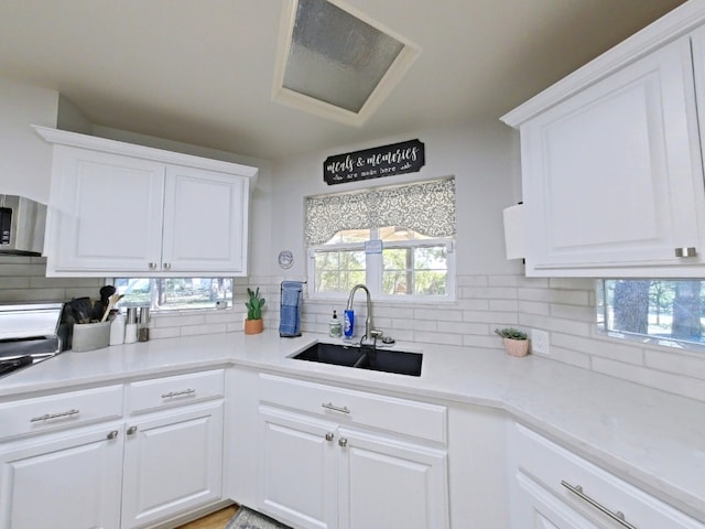 1127 Penion Dr, Austin, TX 78748 - kitchen featuring backsplash, stainless steel microwave, white cabinetry, and light countertops