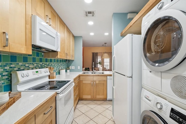 2104 Cullen Ave Unit 223, Austin, TX 78757 - kitchen with white appliances, stacked washer and clothes dryer, a sink, tasteful backsplash, and light countertops