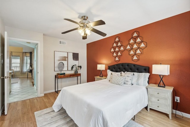 2104 Cullen Ave Unit 223, Austin, TX 78757 - bedroom with an accent wall, light wood-style flooring, baseboards, and a ceiling fan