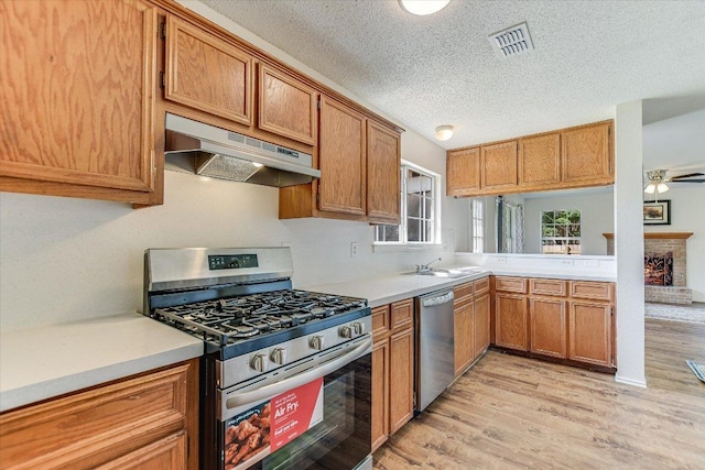 1905 Hollow Tree Blvd, Round Rock, TX 78681 - kitchen with stainless steel appliances, under cabinet range hood, light wood-style floors, a textured ceiling, and light countertops