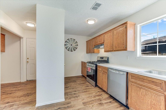 1905 Hollow Tree Blvd, Round Rock, TX 78681 - kitchen with appliances with stainless steel finishes, light wood-type flooring, under cabinet range hood, light countertops, and a textured ceiling