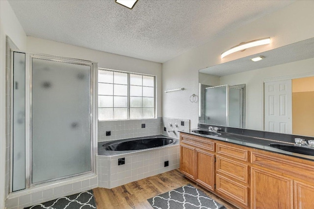 1905 Hollow Tree Blvd, Round Rock, TX 78681 - bathroom with wood finished floors, a shower stall, a garden tub, double vanity, and a textured ceiling