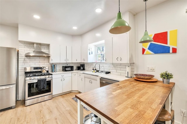 1901 E 10th St, Austin, TX 78702 - kitchen featuring wall chimney exhaust hood, appliances with stainless steel finishes, a sink, a peninsula, and light countertops