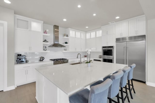 kitchen featuring appliances with stainless steel finishes, wall chimney exhaust hood, open shelves, a sink, and white cabinetry