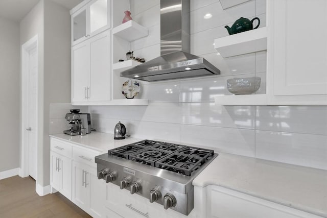kitchen with open shelves, wall chimney range hood, stainless steel gas stovetop, tasteful backsplash, and white cabinets