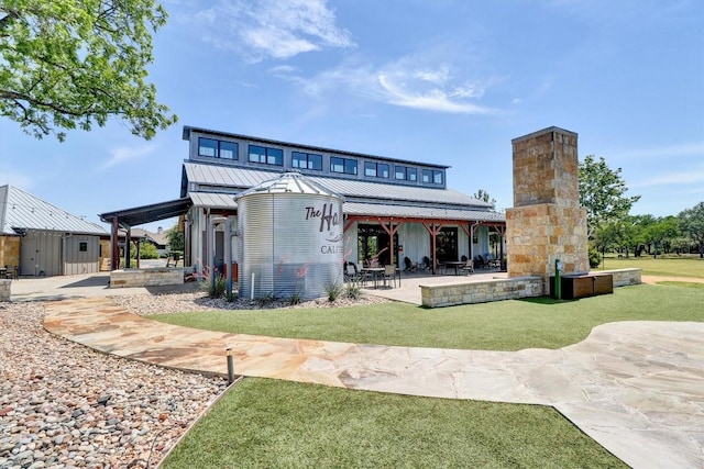 rear view of house with a patio, metal roof, a chimney, a standing seam roof, and a yard