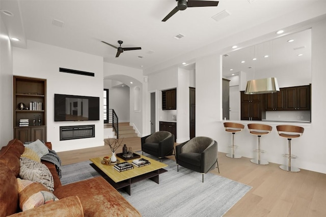 3401 Day Star Cv, Austin, TX 78746 - living area featuring a ceiling fan, light wood-type flooring, recessed lighting, arched walkways, and a glass covered fireplace