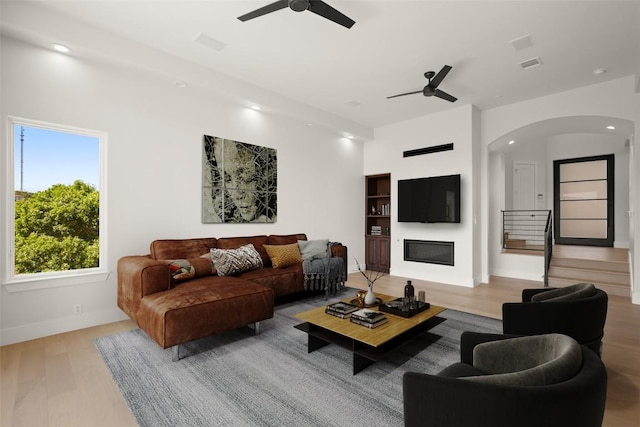 3401 Day Star Cv, Austin, TX 78746 - living area with a ceiling fan, arched walkways, wood finished floors, a glass covered fireplace, and recessed lighting